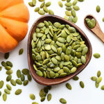 Pumpkin seeds in a wooden bowl on a white table